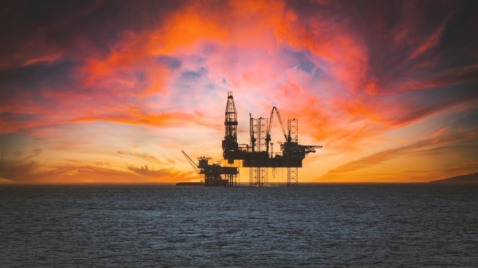 A jack-up rig on open water at sunset